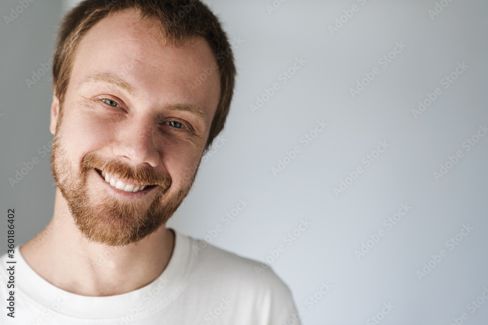 Fototapeta premium Photo of joyful young man with red hair posing and smiling on camera