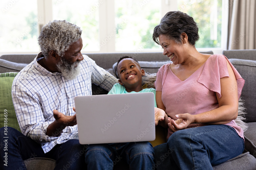 Mixed race boy and his grandparents using a laptop sitting on a couch Mixed race boy and his grandparents using a laptop sitting on a couch