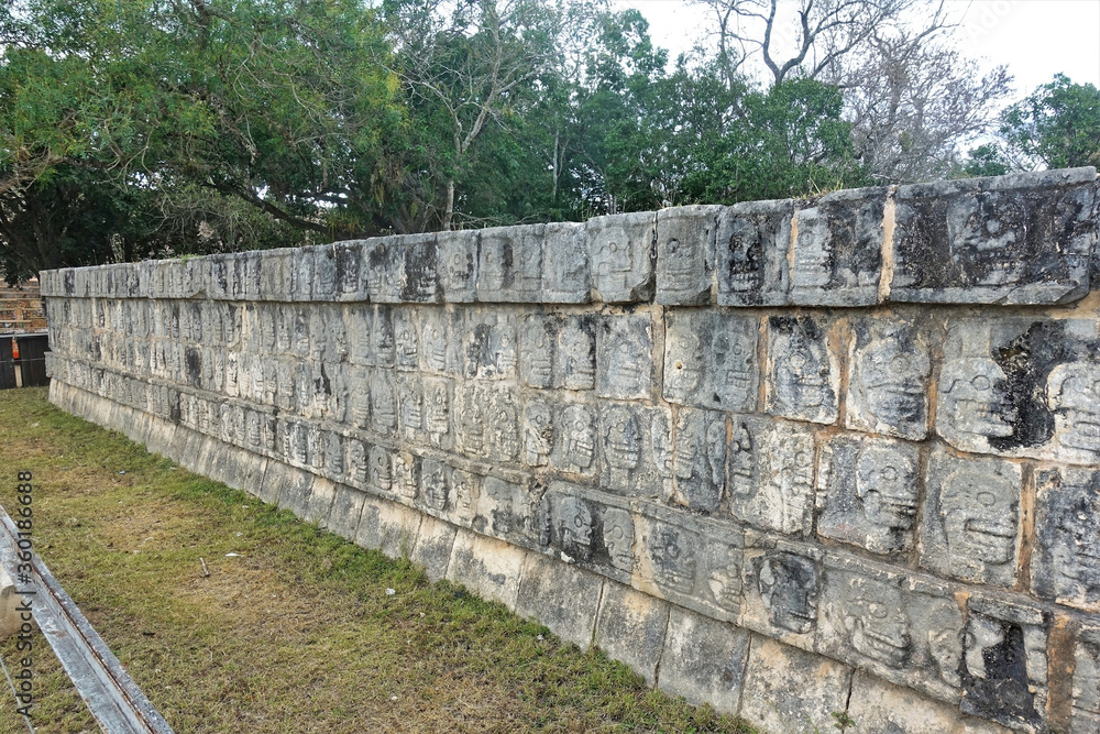 Ancient ruins in Chichen Itza, Mexico. The stone platform of the skulls is decorated with carvings in the form of many human skulls. All drawings are different and are located around the perimeter Ancient ruins in Chichen Itza, Mexico. The stone platform of the skulls is decorated with carvings in the form of many human skulls. All drawings are different and are located around the perimeter