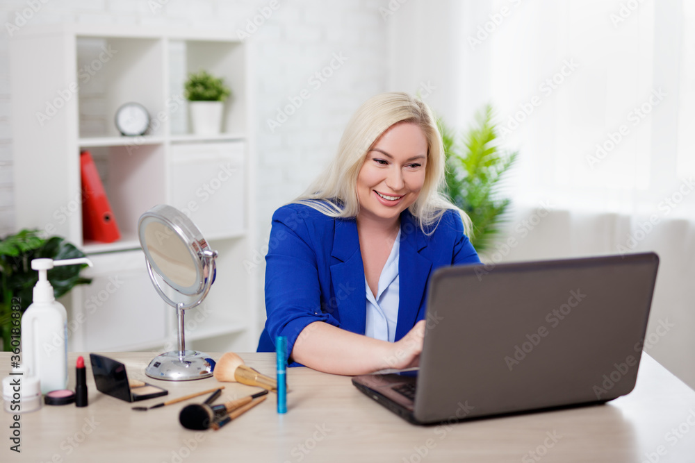 beautiful plus size blonde woman beauty blogger using laptop and applying make up at home beautiful plus size blonde woman beauty blogger using laptop and applying make up at home