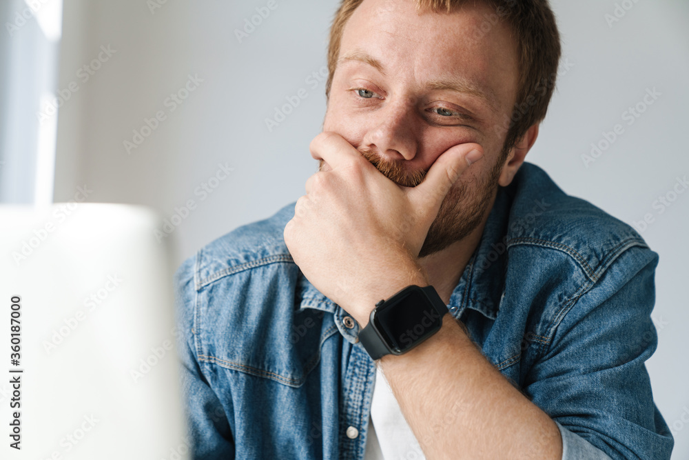 Photo of brooding handsome man wearing smartwatch working with laptop Photo of brooding handsome man wearing smartwatch working with laptop