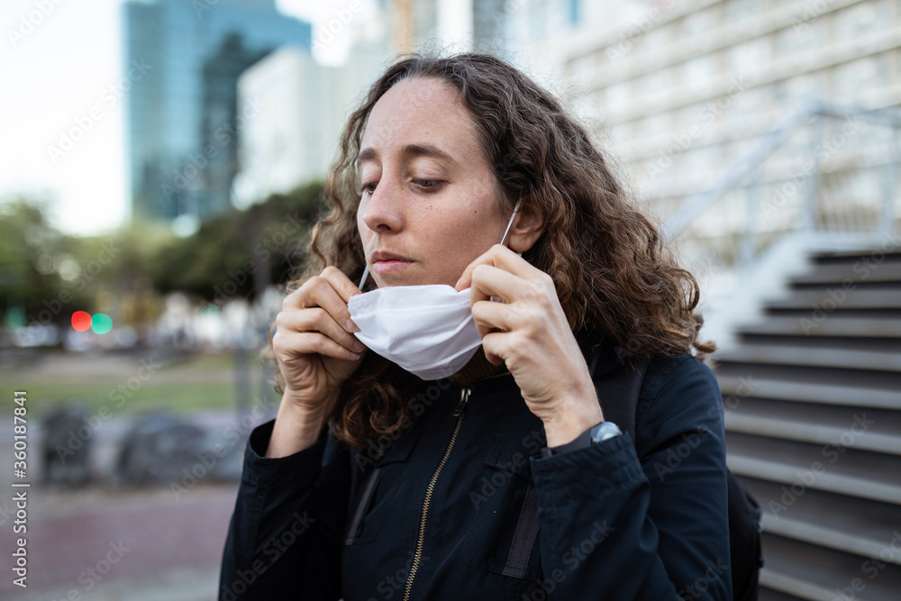 Caucasian woman putting on mask in the streets Caucasian woman putting on mask in the streets