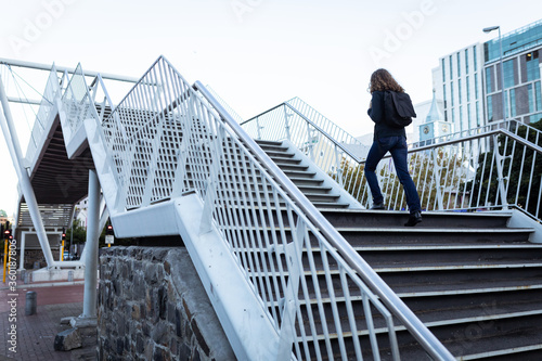 Caucasian woman wearing a protective mask and walking up the stairs