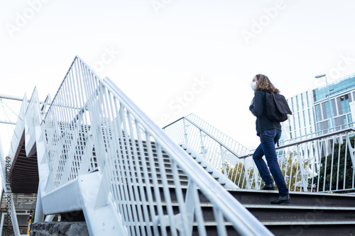 Caucasian woman wearing a protective mask and walking up the stairs