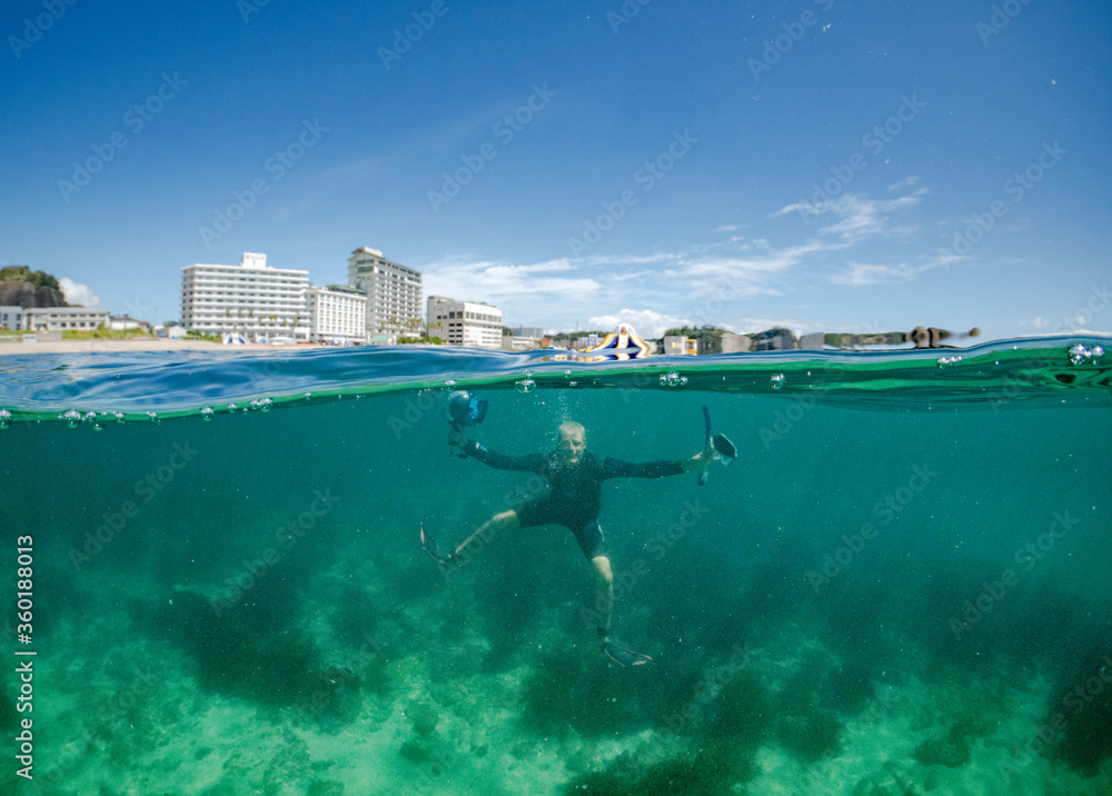 Snorkelling in Japan an underwater world full of seaweed and amazing seascapes. A caucasioan man swimming underwater.
