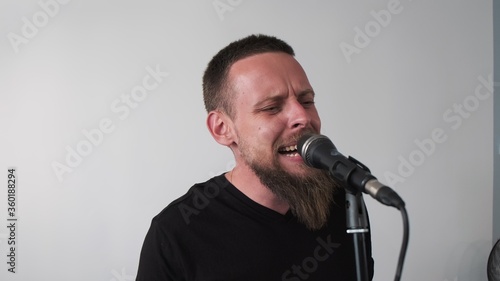 Young musician singing into microphone while recording new song at home