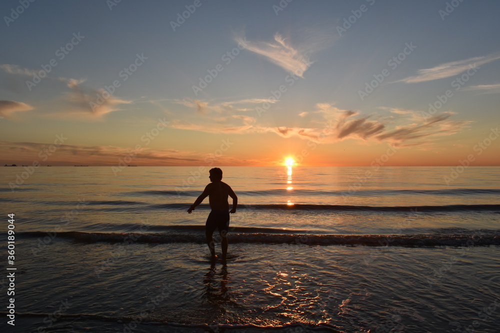 Katwijk aan Zee / The Netherland - June 20 2020: Local sports fishermen are walking in the sea, trawling their fishnet along the beach fishing for sole, in the evening at sun set. 