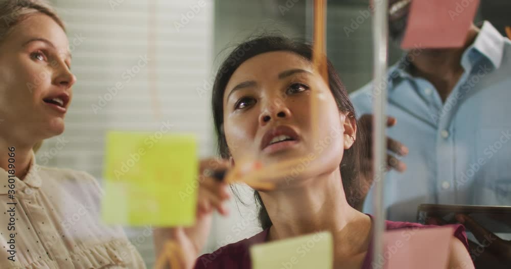 Professional businesspeople discussing while writing on the whiteboard in modern office in slow moti Professional businesspeople discussing while writing on the whiteboard in modern office in slow moti