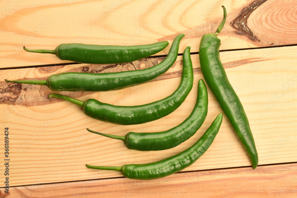 Green chili pepper in a cut, close-up, on a wooden table. Green chili pepper in a cut, close-up, on a wooden table.