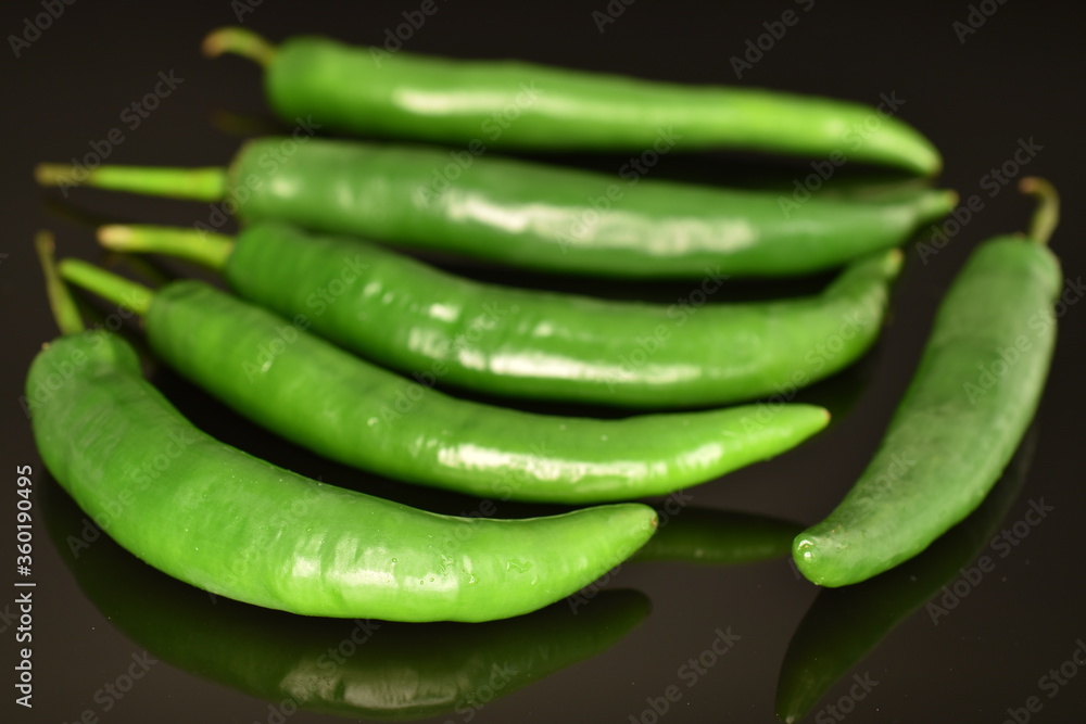 Green chili pepper, close-up, on a black background. Green chili pepper, close-up, on a black background.