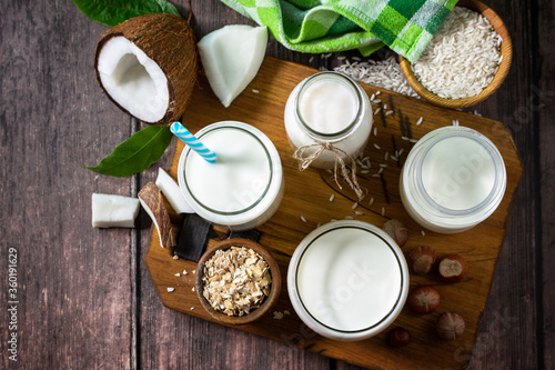 Food and drink, health care, diet and nutrition concept. Vegan alternative nut milk from coconut, nuts, oatmeal, rice on a kitchen table. Top view flat lay background. Copy space.