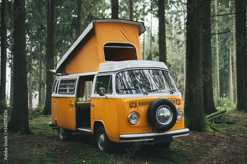 Orange retro Bulli Vintage Camper in green forest.