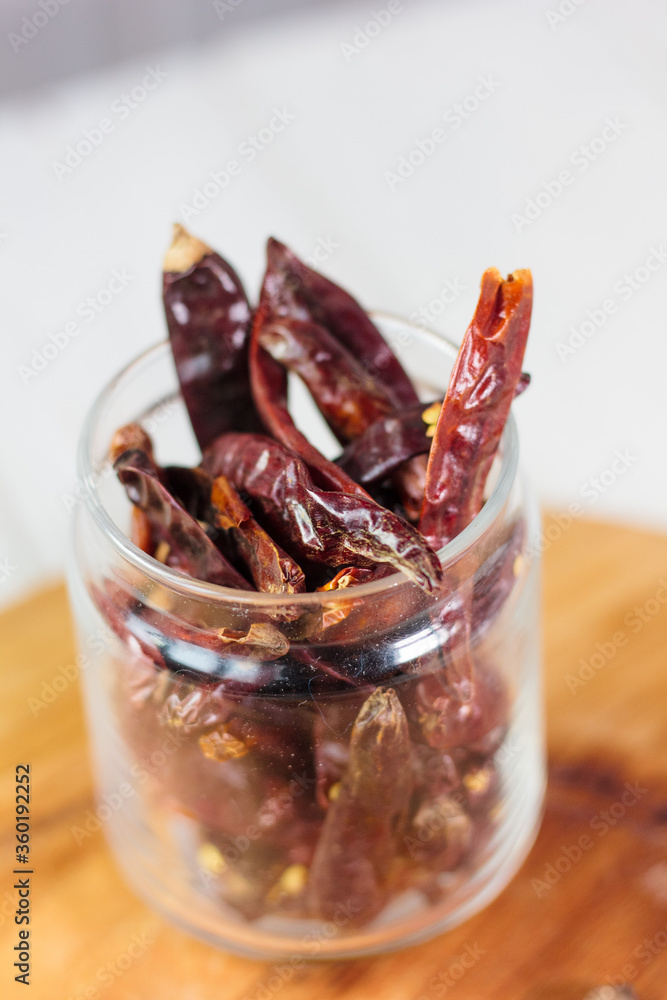 Dry chili peppers in a glass jar over wooden board Dry chili peppers in a glass jar over wooden board