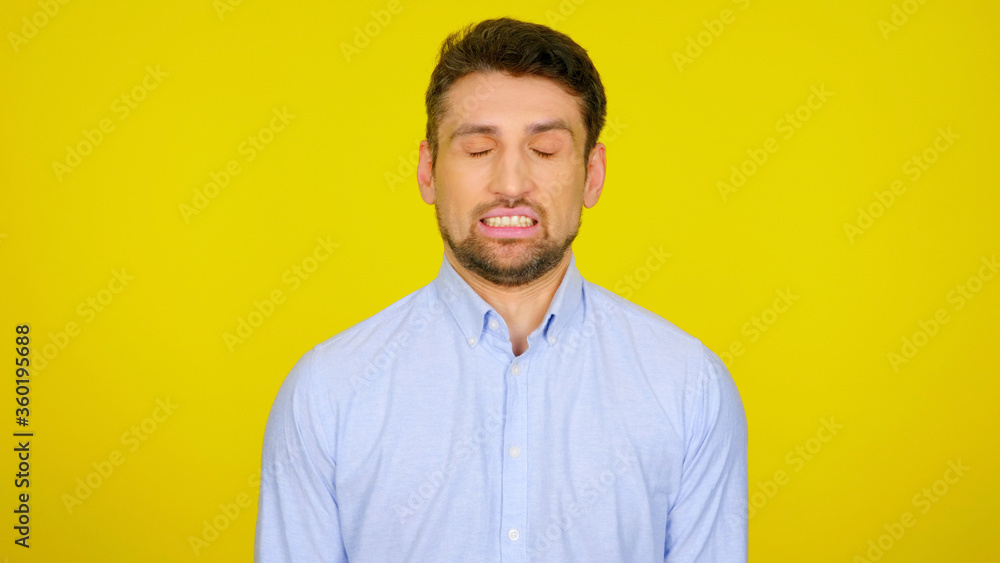 Bearded man with his eyes closed and mouth open is leaning showing teeth. Handsome guy in a light blue shirt on a yellow background with copyspace. Place for text or product Bearded man with his eyes closed and mouth open is leaning showing teeth. Handsome guy in a light blue shirt on a yellow background with copyspace. Place for text or product