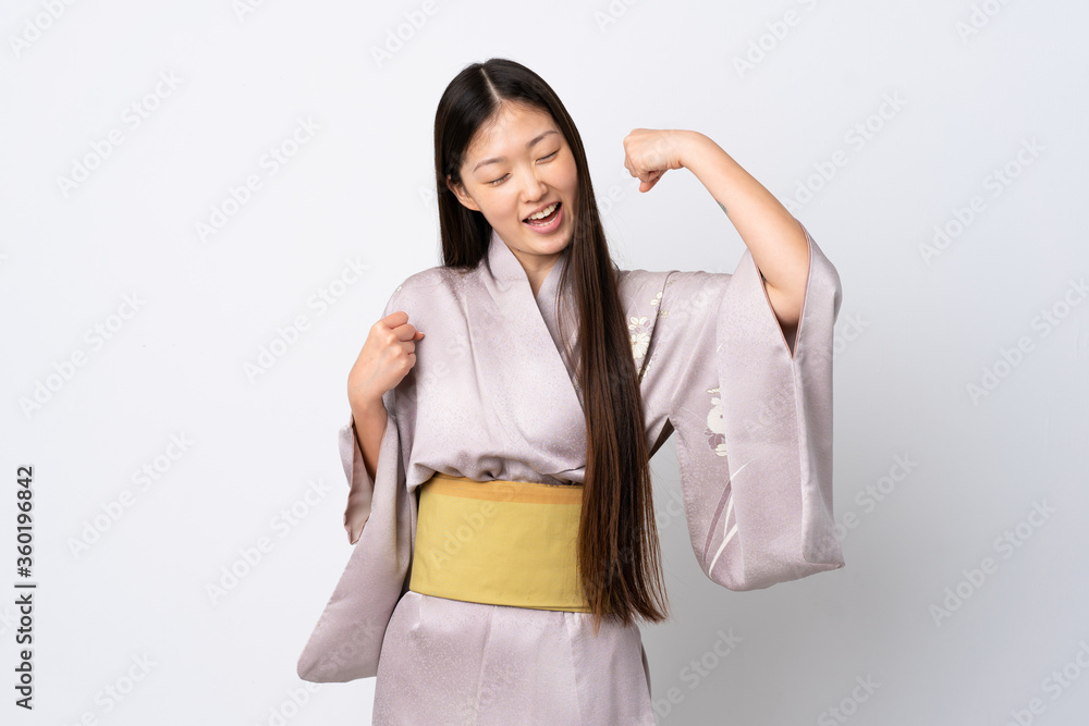 Young Chinese girl wearing kimono over isolated background celebrating a victory Young Chinese girl wearing kimono over isolated background celebrating a victory