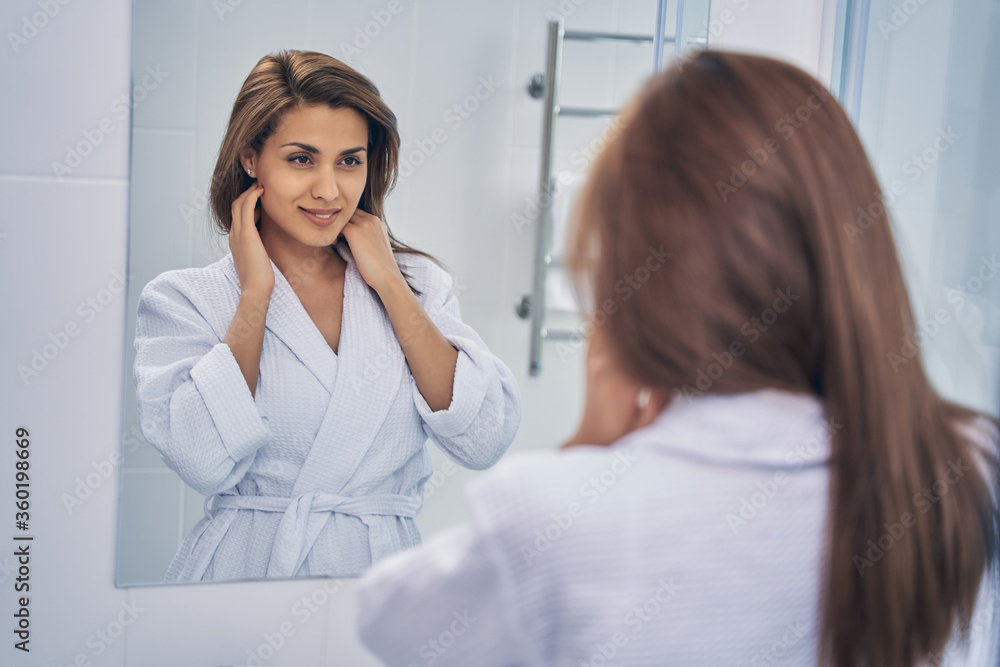 Charming young woman looking in the mirror in the morning Charming young woman looking in the mirror in the morning