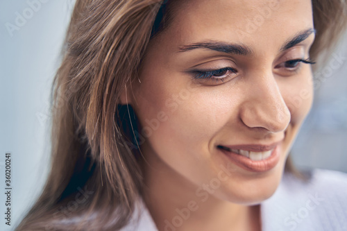 Charming young woman looking down and smiling