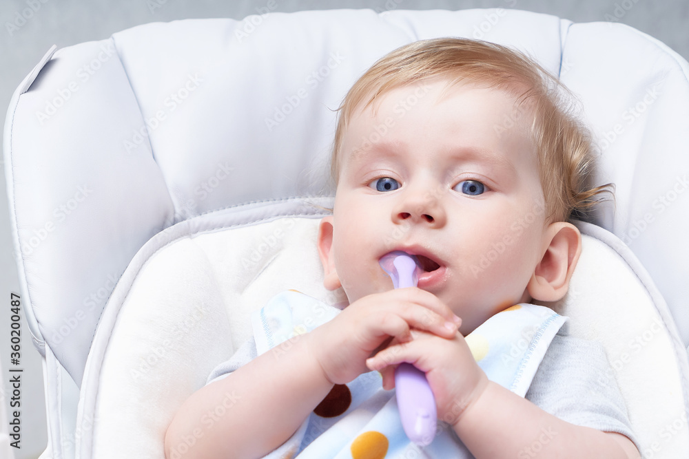 Cute baby in a child seat eats porridge. First lure Close up Cute baby in a child seat eats porridge. First lure Close up