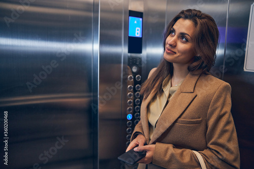 Successful business lady going down in elevator photo