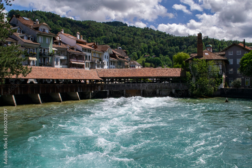 view of the turbulent river flow at the dam and beautiful houses near the coast in Switzerland in Thun