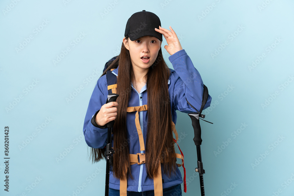 Young Chinese girl with backpack and trekking poles over isolated blue background has realized something and intending the solution Young Chinese girl with backpack and trekking poles over isolated blue background has realized something and intending the solution