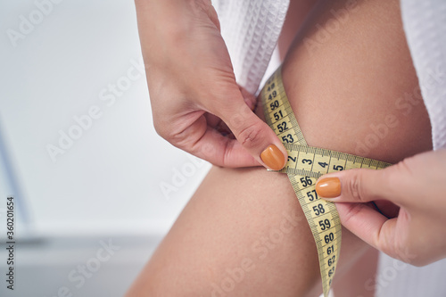 Young woman measuring hip with tape measure