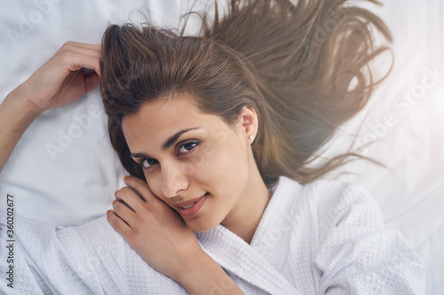 Attractive young woman resting on white sheets