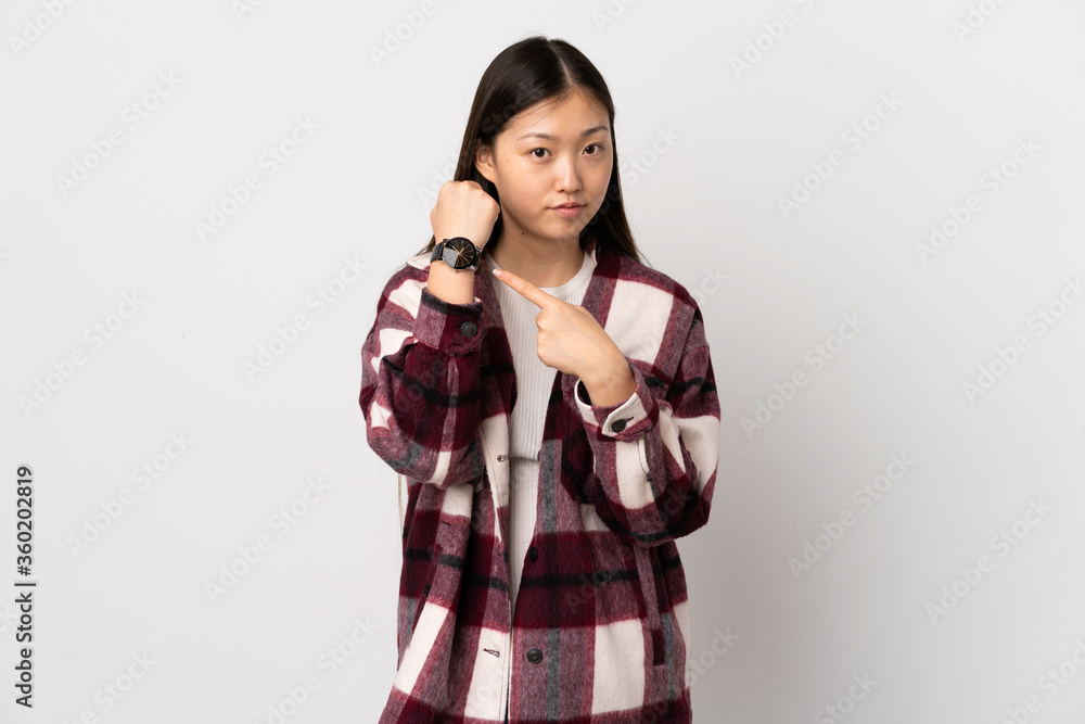 Young Chinese girl over isolated white background making the gesture of being late Young Chinese girl over isolated white background making the gesture of being late