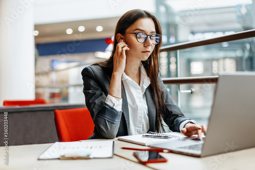 Girl works on a laptop in the workplace. Successful business woman creates a startup and makes decisions.