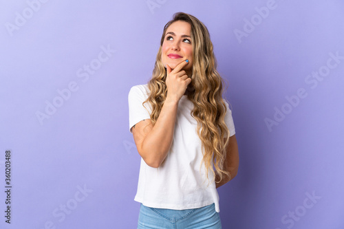 Young Brazilian woman isolated on purple background and looking up
