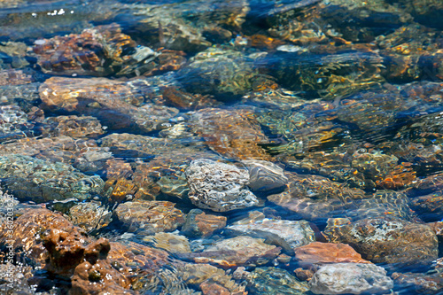 crystal sea water and colourful stones on the beach. sunny day. selective focus