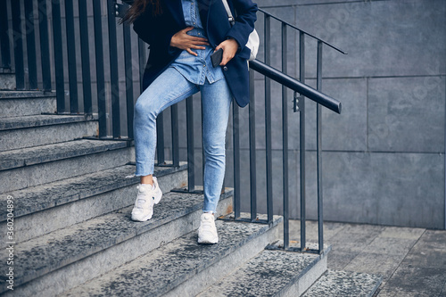 Female in jeans touching her belly outdoors