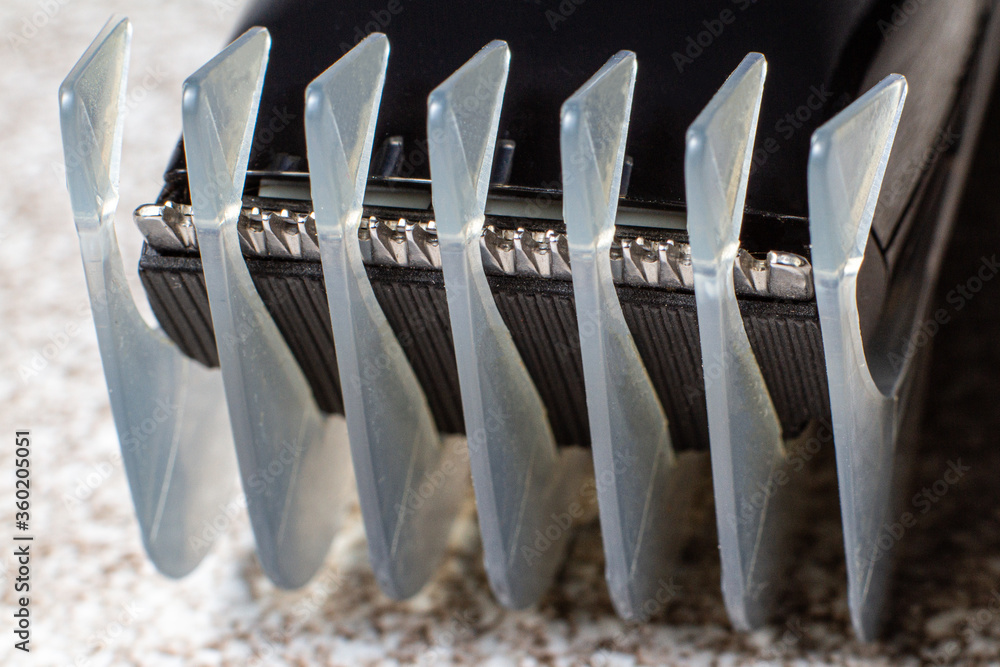 Fototapeta premium A razor with a trimmer for cutting and shaving hair, with a comb nozzle. Care for beard and hair