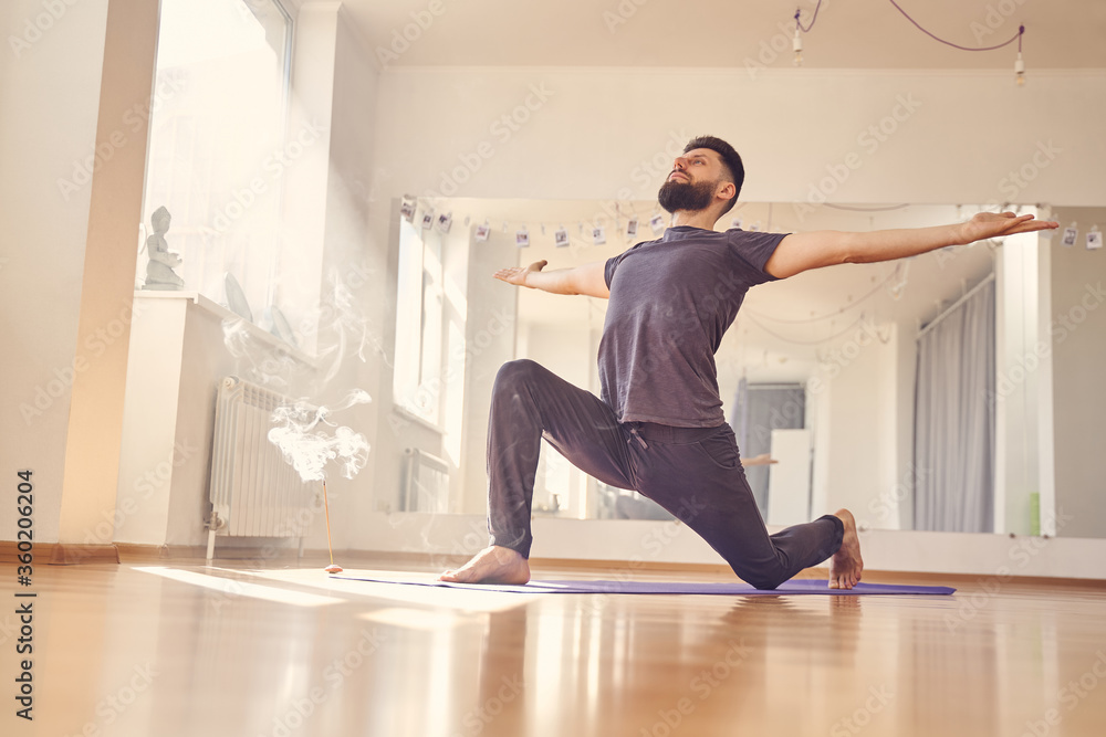 Fototapeta premium Handsome bearded man in shirt doing yoga exercise