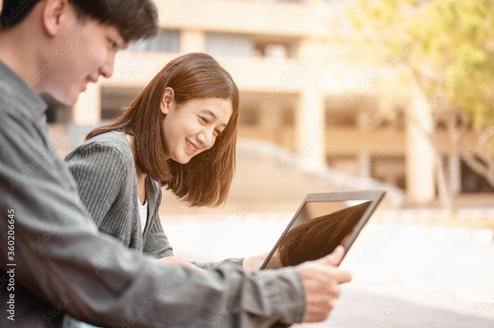Two students reading the book and learning by laptop at stairs in university. Two students reading the book and learning by laptop at stairs in university.