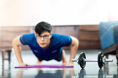 Fototapeta Naklejka Na Ścianę i Meble -  Mature Asian man Doing Exercises at Home. workout at home. social distancing.