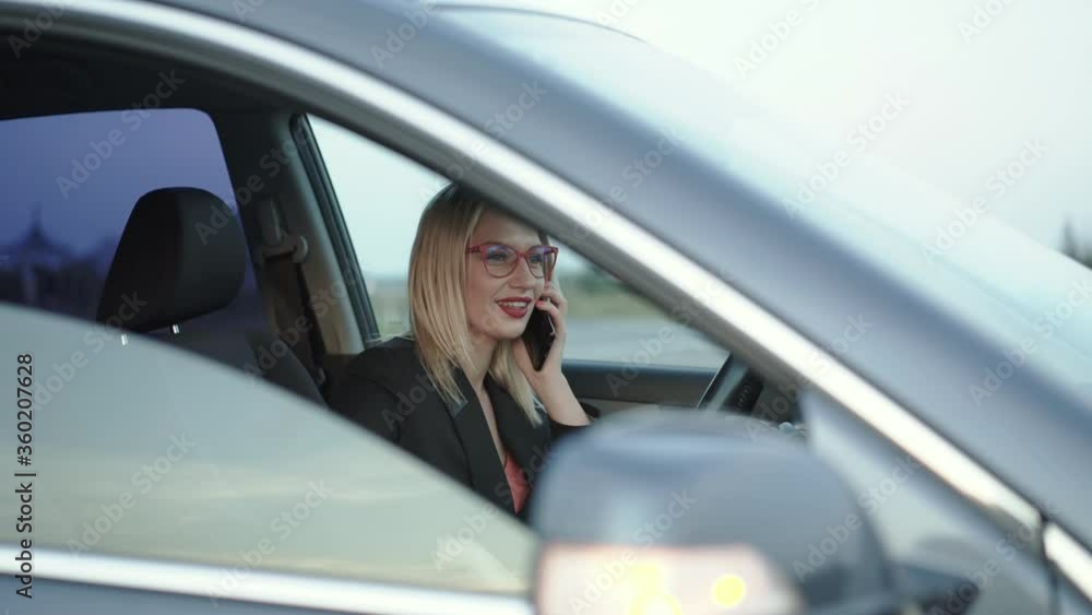 Happy blonde talks with smile on the smartphone when relaxes in the car Happy blonde talks with smile on the smartphone when relaxes in the car