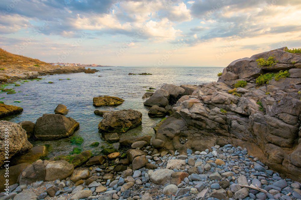 sea beach with pebbles and rocks. beautiful landscape with clouds on the sky at sunrise. wide panoramic view of a bay