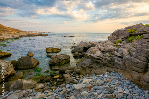 sea beach with pebbles and rocks. beautiful landscape with clouds on the sky at sunrise. wide panoramic view of a bay