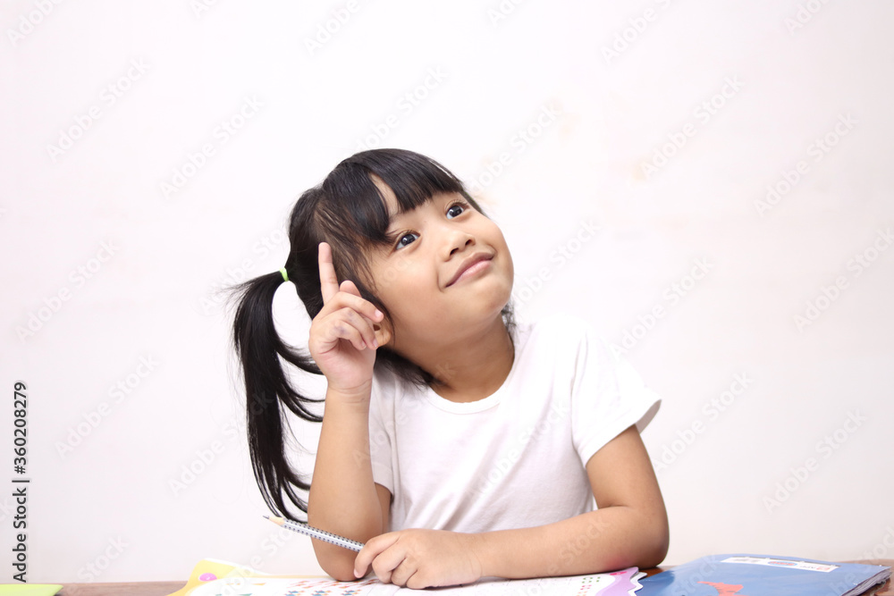 Cute litle Asian baby girl holding pen and book, studying and learning while thinking something or having good idea, smiling and looking up, imagination Cute litle Asian baby girl holding pen and book, studying and learning while thinking something or having good idea, smiling and looking up, imagination