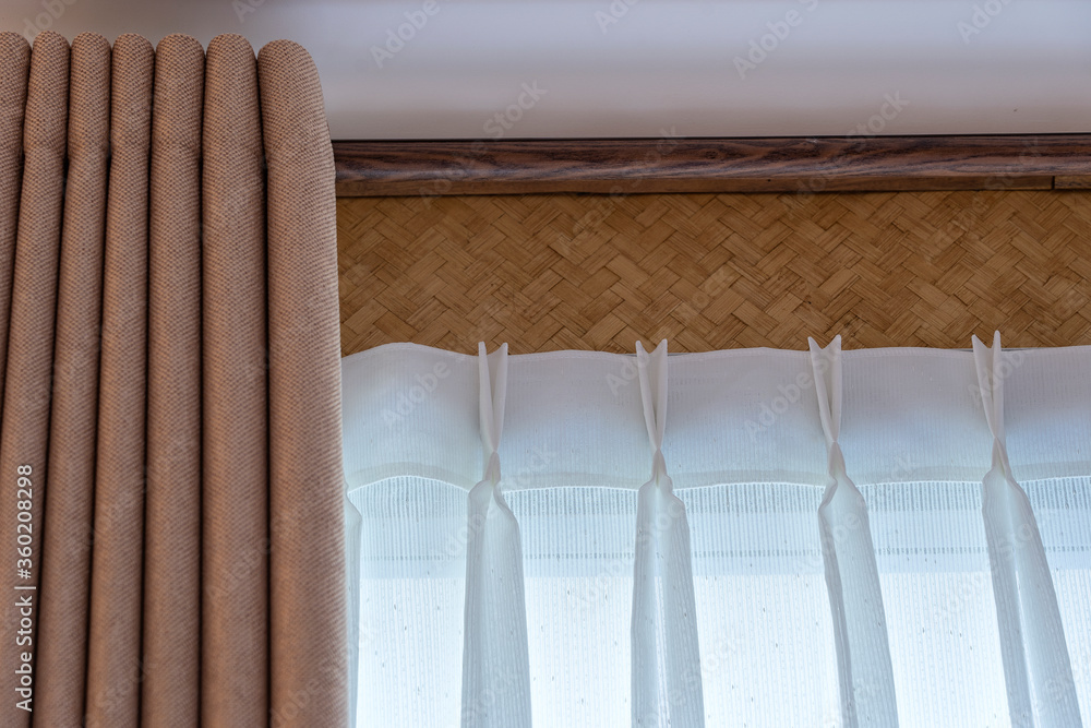 Window beige curtains and white tulle on the curtain rod