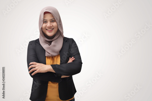 Asian muslim businesswoman wearing hijab smiling friendly with arms crossed, successful confident young woman © airdone