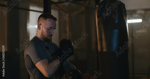 MS Caucasian male puts on boxing gloves in a boxing studio before training © supamotion