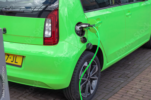 Green Electric car on charching station plugged