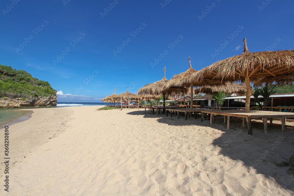row of hut with thacthed roof at Ndrini Beach, Yogyakarta, Indonesia. tropical beach resort