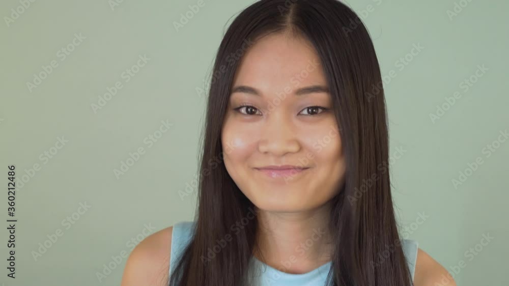 Funny Japanese girl nods and says yes. video blue isolated background. 4K Funny Japanese girl nods and says yes. video blue isolated background. 4K