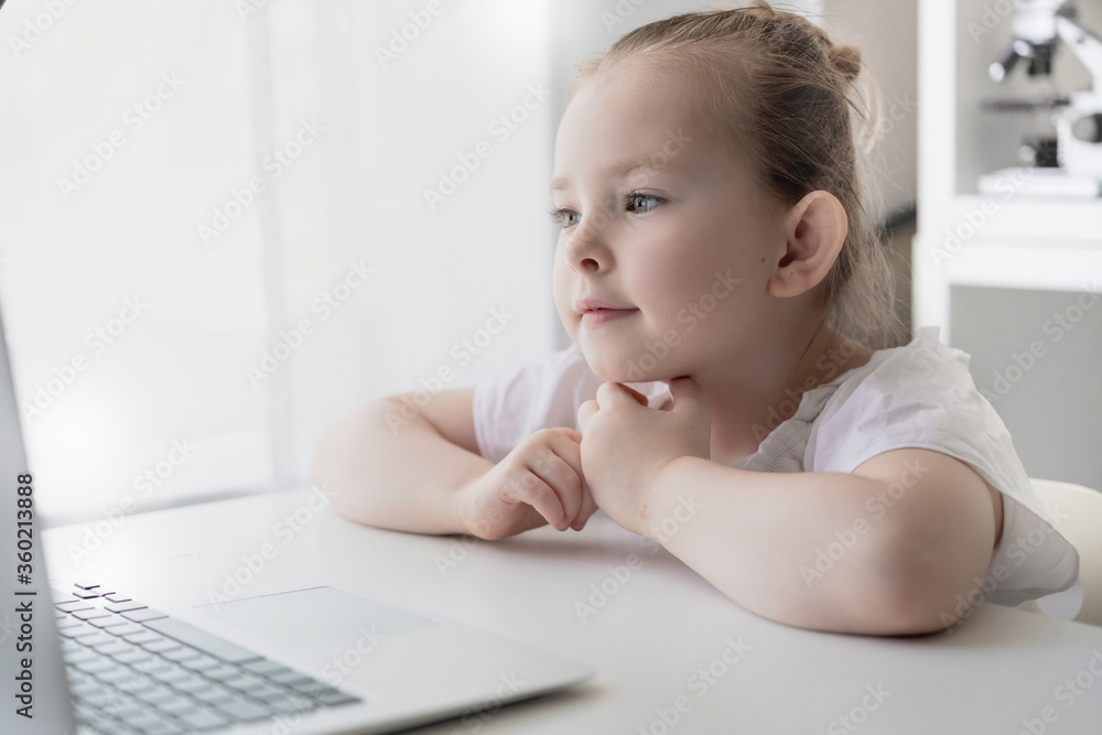 Cute little girl using laptop at home. Education, online study, home studying The girl at home communicates with friends on the Internet. Kids distance learning. High quality photo Cute little girl using laptop at home. Education, online study, home studying The girl at home communicates with friends on the Internet. Kids distance learning. High quality photo