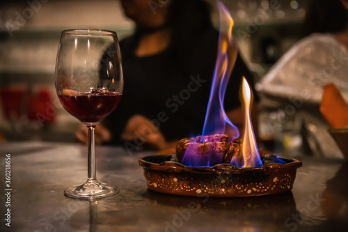 Traditional portuguese sausage chourico aka spanish chorizo sliced and flame-cooked over alcohol in an earthenware dish served with a glass of chilled red port wine, a fado house, Lisbon, Portugal photo
