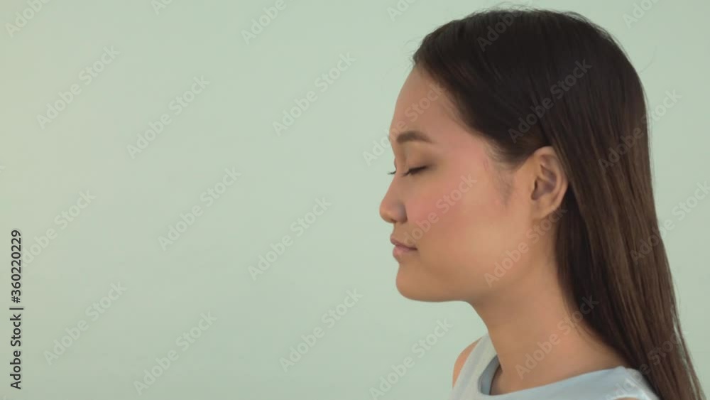 Profile, close-up, Sarcastic Asian girl Nods. False information. . video blue isolated background. 4K Profile, close-up, Sarcastic Asian girl Nods. False information. . video blue isolated background. 4K
