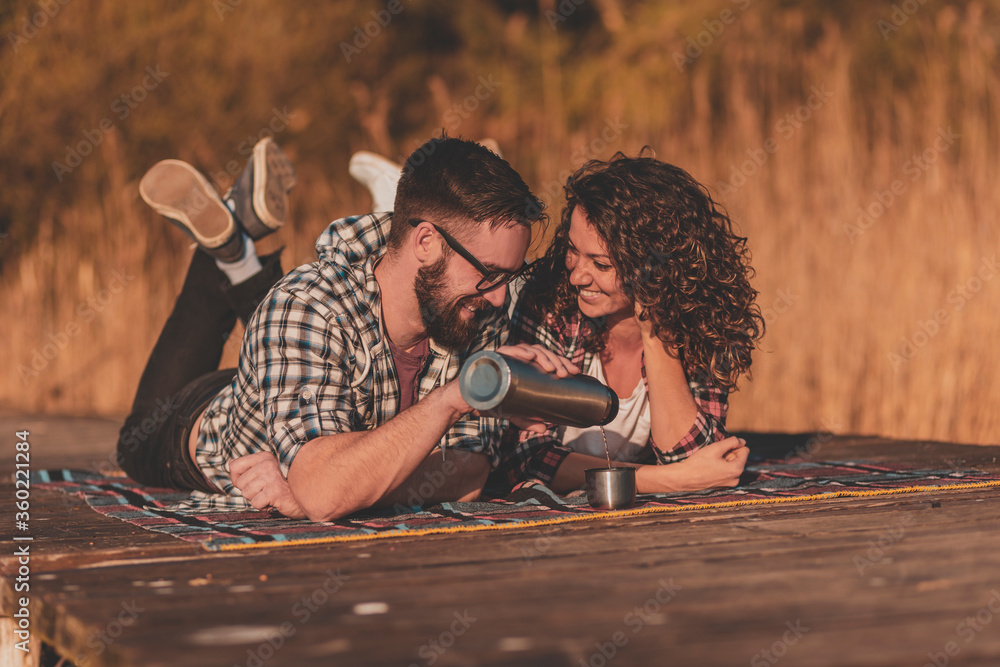 Couple drinking tea at lake docks picnic